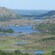 Lowlands covered in trees, grass and bodies of water near hills